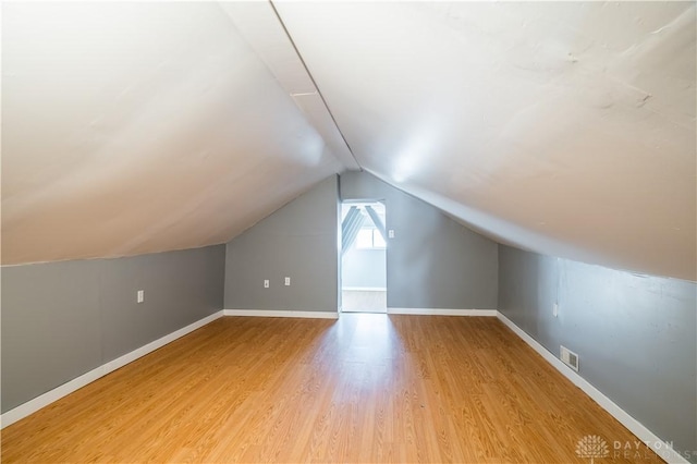 bonus room with visible vents, baseboards, light wood-type flooring, and lofted ceiling