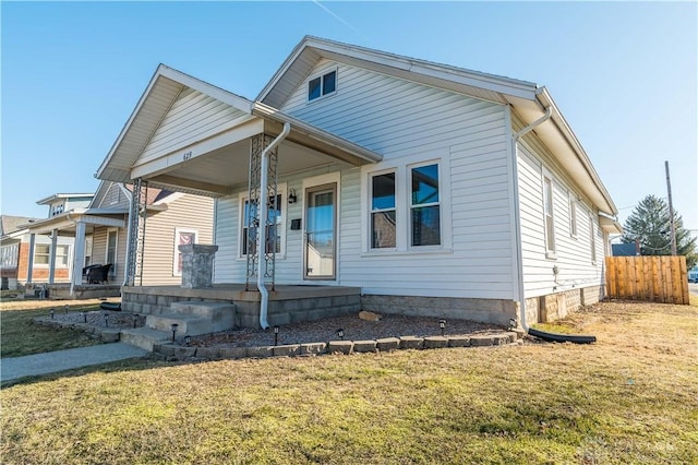 bungalow-style house with a porch, a front yard, and fence