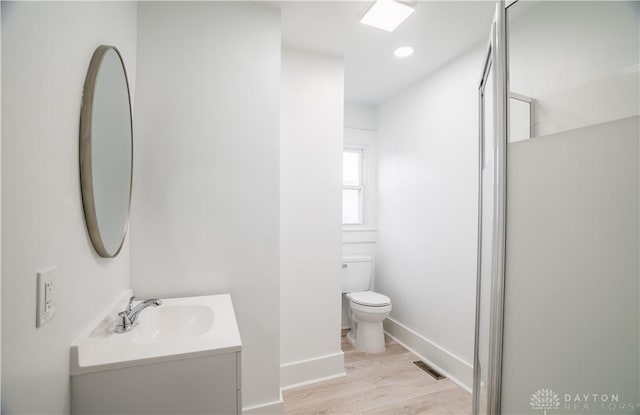 bathroom featuring visible vents, toilet, wood finished floors, baseboards, and vanity