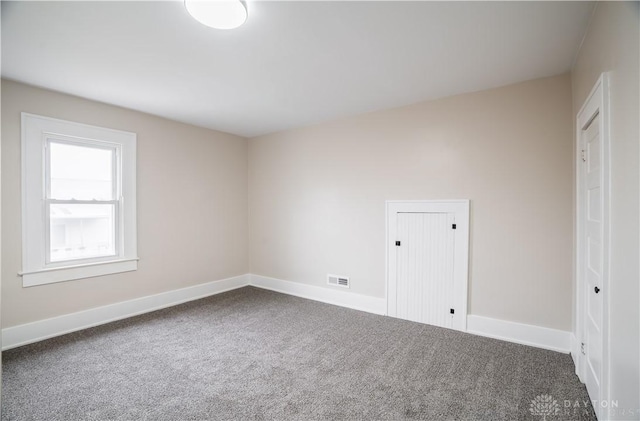 empty room featuring carpet flooring, visible vents, and baseboards