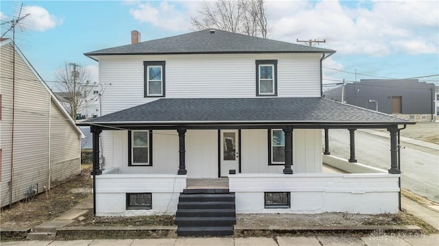 view of front of house with roof with shingles, a porch, and a chimney