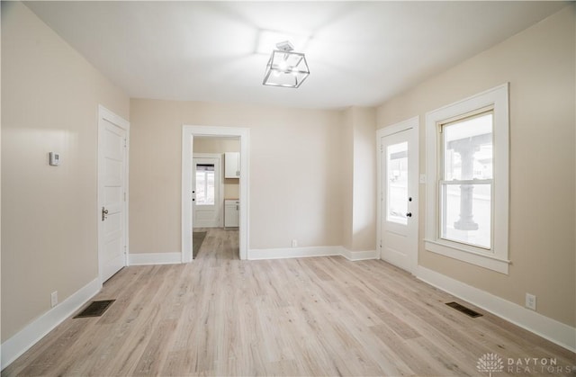 unfurnished dining area featuring light wood finished floors, visible vents, and baseboards