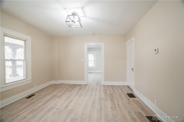 empty room featuring visible vents, light wood-style floors, and baseboards