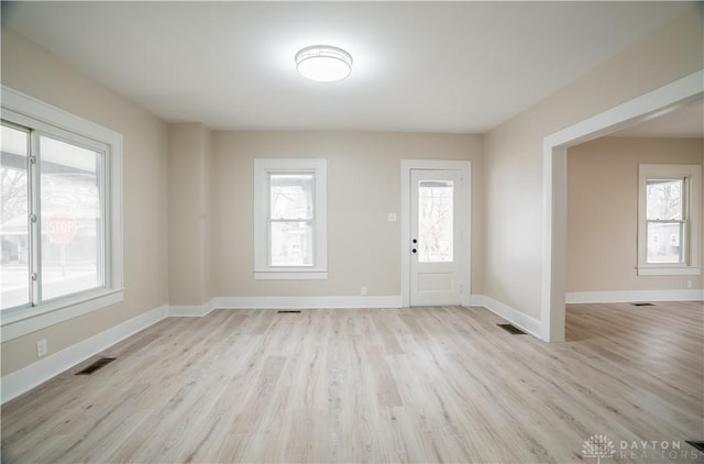 foyer entrance with light wood-type flooring, visible vents, and a healthy amount of sunlight