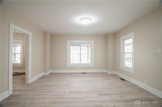 unfurnished room featuring visible vents, a healthy amount of sunlight, light wood-type flooring, and baseboards