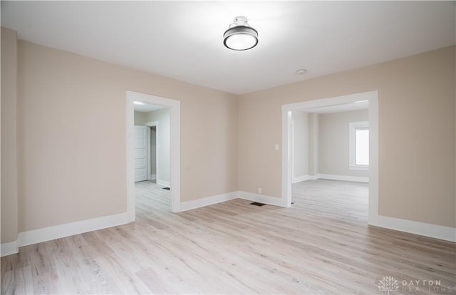 unfurnished room with visible vents, light wood-style flooring, and baseboards