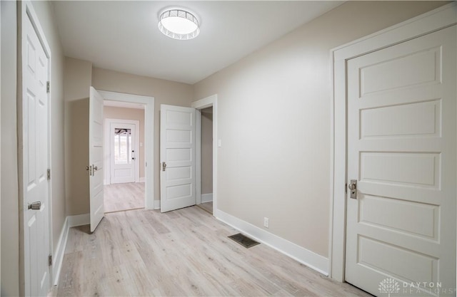 unfurnished bedroom with visible vents, light wood-style flooring, and baseboards