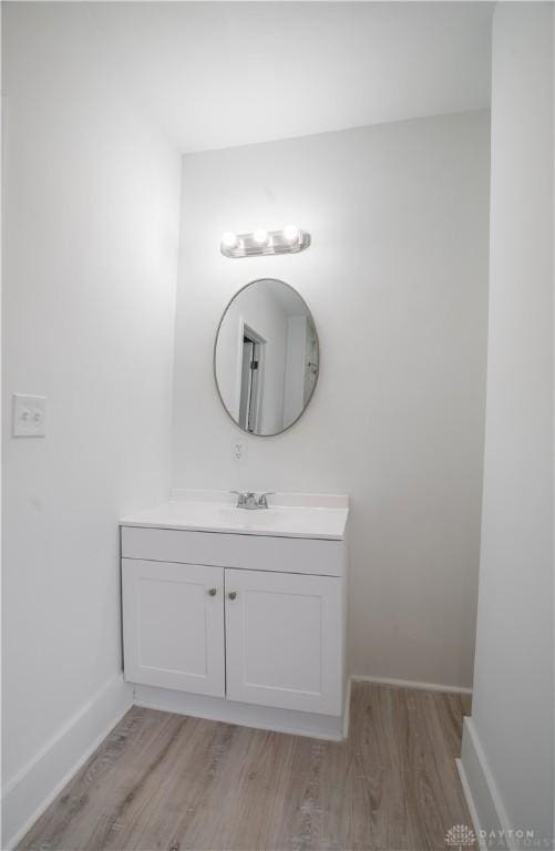 bathroom with baseboards, wood finished floors, and vanity