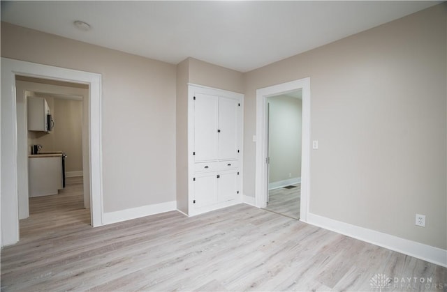 unfurnished bedroom with a closet, baseboards, and light wood finished floors