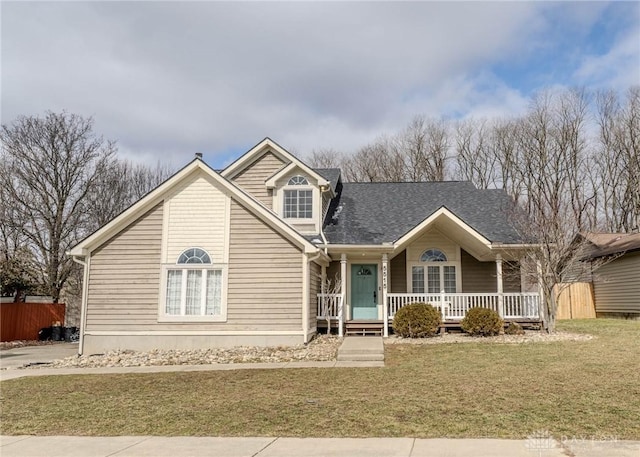 traditional-style house featuring covered porch, a shingled roof, a front yard, and fence