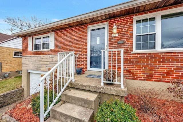 entrance to property with a garage, stone siding, and brick siding