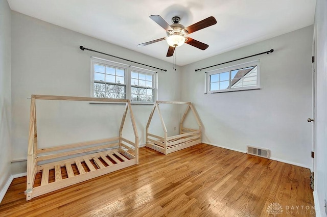 spare room featuring visible vents, baseboards, wood finished floors, and a ceiling fan