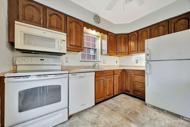 kitchen featuring brown cabinetry, white appliances, light countertops, and a sink