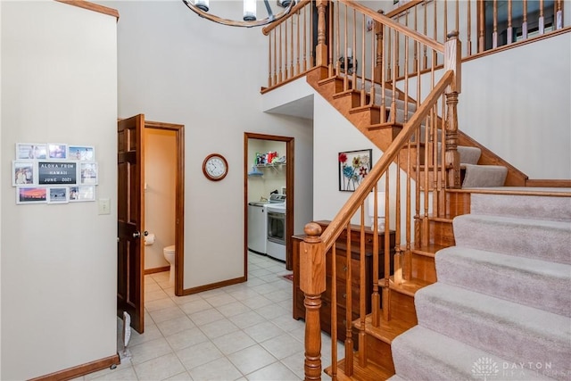 staircase featuring baseboards and a towering ceiling