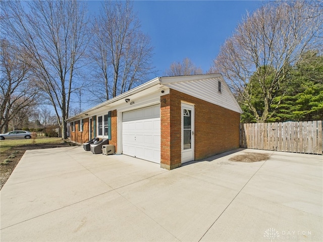 garage featuring concrete driveway and fence