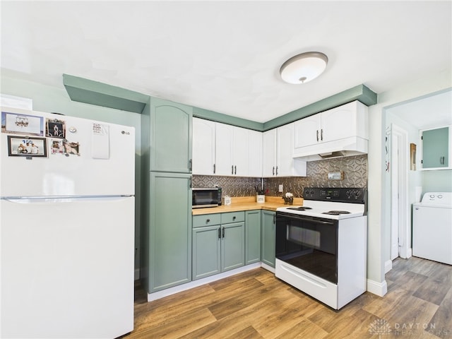 kitchen featuring under cabinet range hood, stainless steel microwave, washer / clothes dryer, electric range oven, and freestanding refrigerator