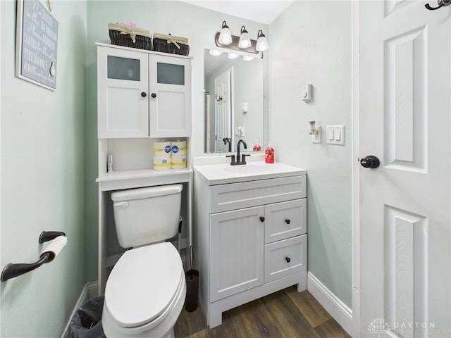 bathroom featuring vanity, toilet, wood finished floors, and baseboards