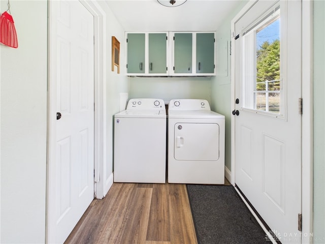 laundry room with washing machine and dryer, cabinet space, and wood finished floors