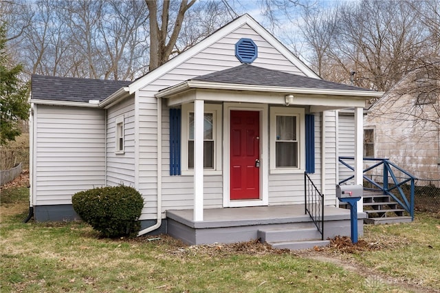 view of front of property with roof with shingles and a front yard