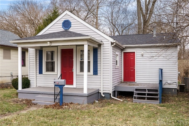 view of front of property featuring a front yard, cooling unit, fence, covered porch, and a shingled roof