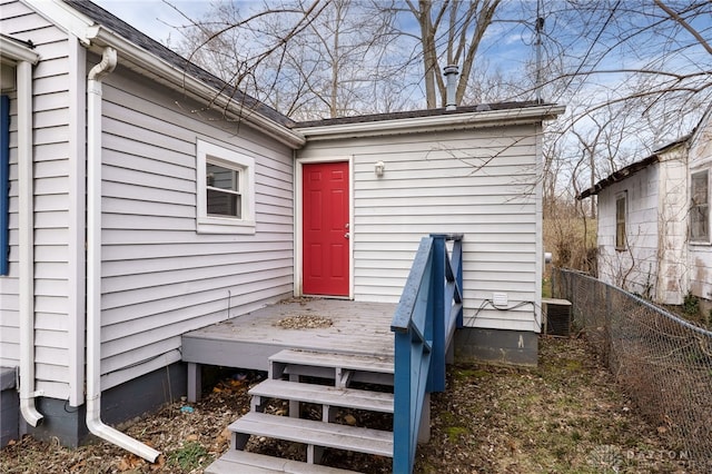 doorway to property featuring central AC unit and fence