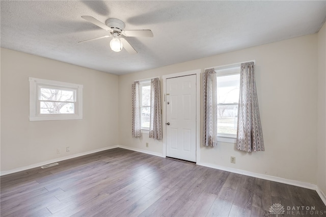 foyer with a ceiling fan, visible vents, baseboards, dark wood-style flooring, and a textured ceiling