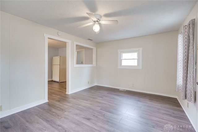 unfurnished room featuring visible vents, a ceiling fan, a textured ceiling, wood finished floors, and baseboards