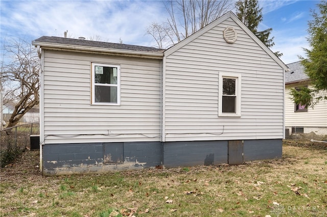 view of property exterior with a lawn and fence