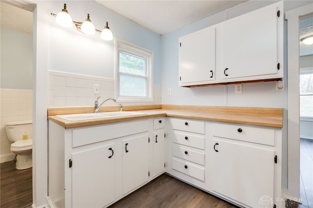 kitchen with white cabinets, tile walls, light countertops, and a sink