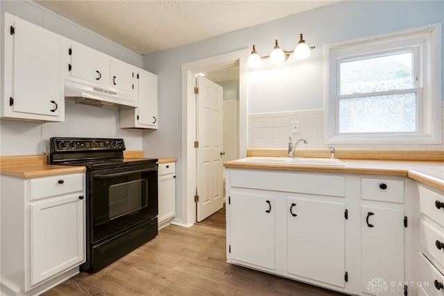 kitchen with under cabinet range hood, black electric range oven, light countertops, and a sink