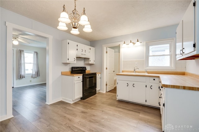 kitchen featuring under cabinet range hood, light wood-style flooring, black electric range oven, white cabinetry, and a sink