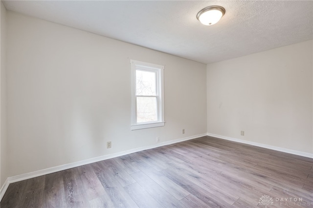 unfurnished room featuring baseboards, a textured ceiling, and wood finished floors