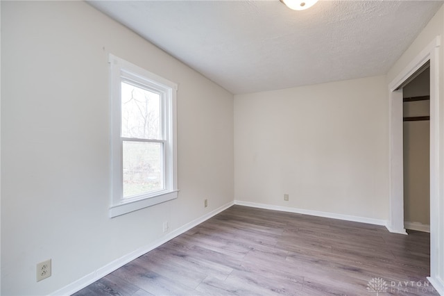 unfurnished bedroom featuring baseboards, a textured ceiling, and wood finished floors