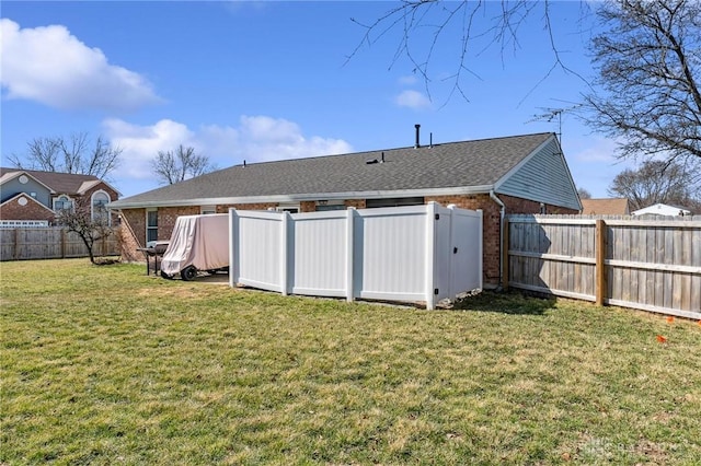 back of property featuring a yard, a fenced backyard, and brick siding