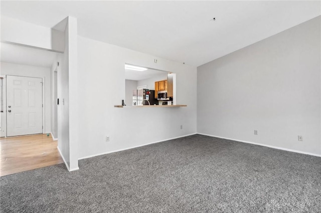 unfurnished living room with carpet flooring and baseboards