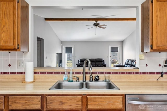 kitchen featuring open floor plan, lofted ceiling with beams, light countertops, stainless steel dishwasher, and a sink