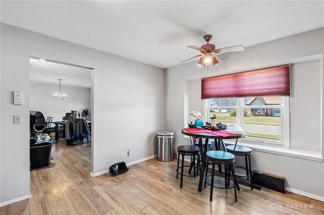 dining space featuring ceiling fan with notable chandelier, wood finished floors, and baseboards