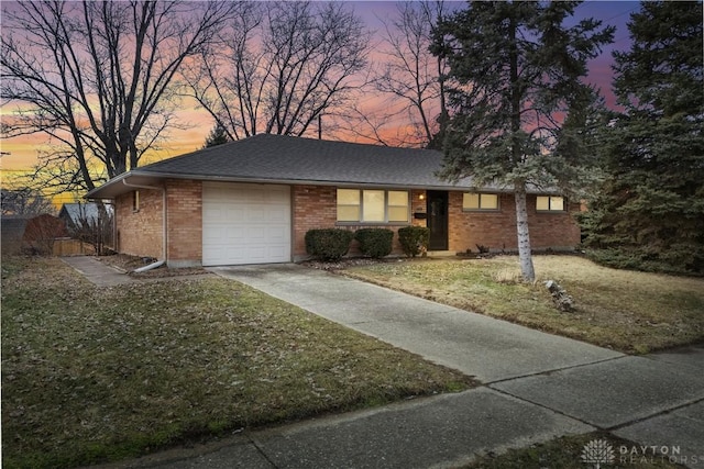 single story home with an attached garage, a yard, a shingled roof, concrete driveway, and brick siding