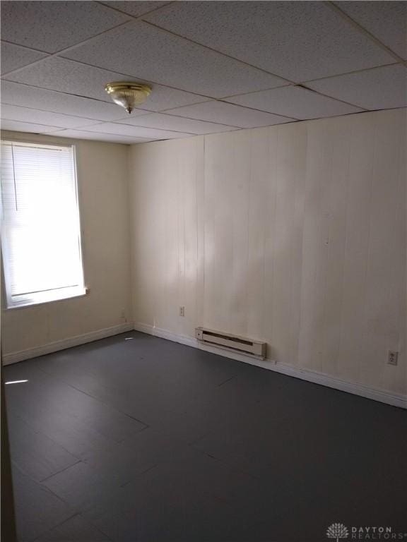 empty room with a baseboard heating unit and a paneled ceiling