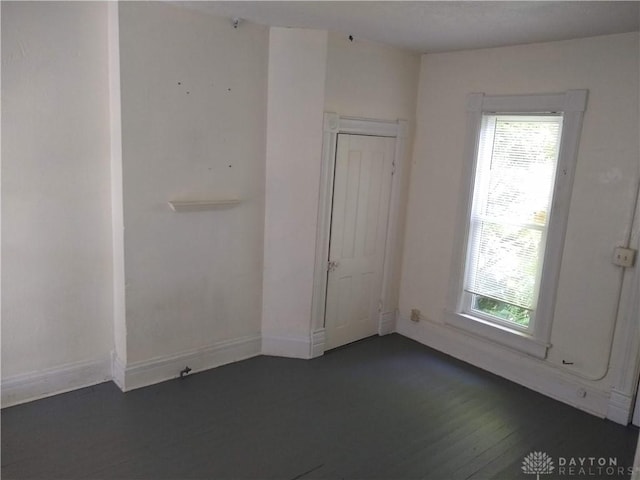 spare room with dark wood-style floors and baseboards