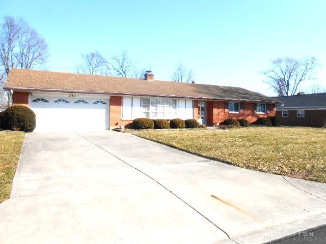 single story home with a front lawn, a chimney, concrete driveway, and an attached garage