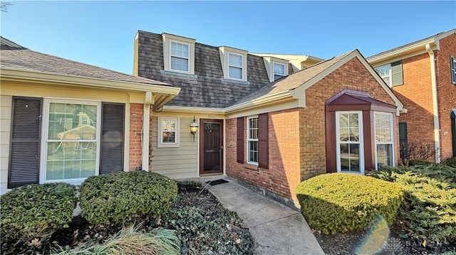 property entrance with brick siding and a shingled roof