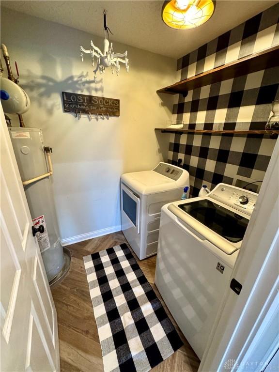 washroom featuring baseboards, washing machine and clothes dryer, dark wood finished floors, laundry area, and water heater