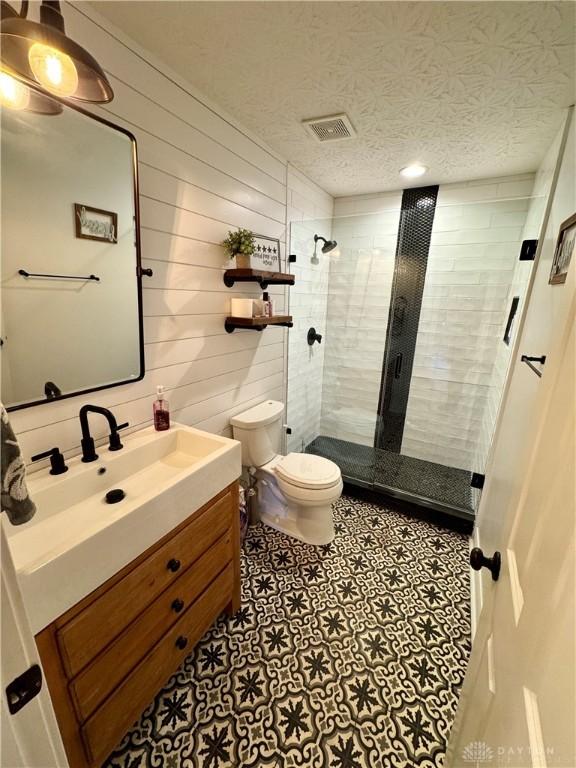 full bathroom featuring visible vents, toilet, a stall shower, a textured ceiling, and vanity