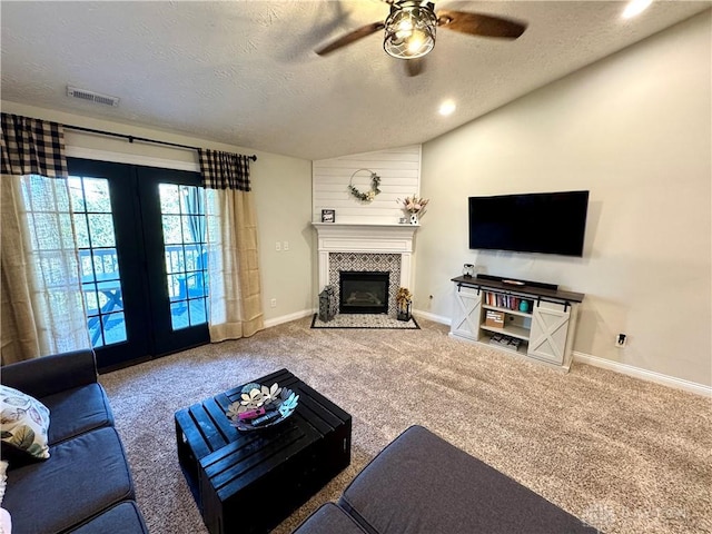 living area with a ceiling fan, carpet, visible vents, a fireplace with flush hearth, and vaulted ceiling