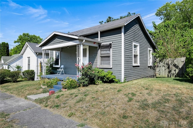 bungalow with covered porch, a front lawn, and fence