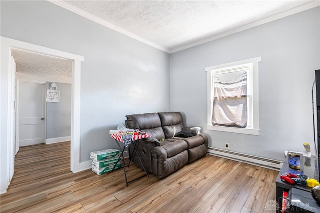 sitting room with a baseboard heating unit, a textured ceiling, light wood-style flooring, and ornamental molding