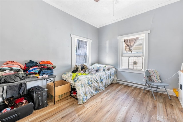 bedroom featuring ceiling fan, a baseboard radiator, wood finished floors, and ornamental molding