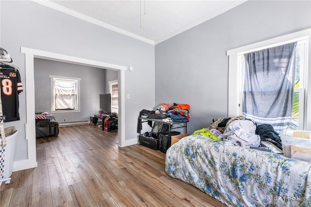 bedroom featuring a baseboard heating unit, crown molding, baseboards, and hardwood / wood-style floors