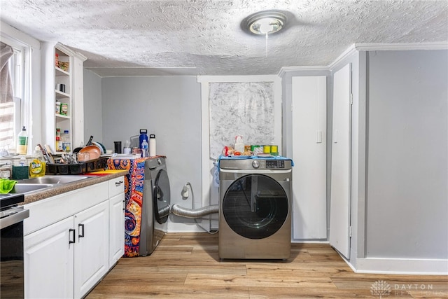 laundry room with a textured ceiling, washer / dryer, and light wood-style flooring